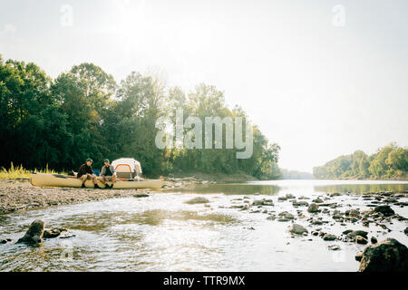 Friends sitting on boat at lakeshore against clear sky Stock Photo