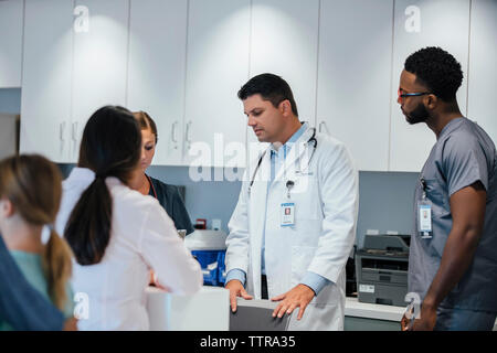 Doctors working at hospital reception with patient in foreground Stock Photo