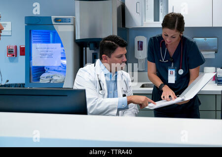 Doctor and nurse reviewing documents at hospital reception Stock Photo