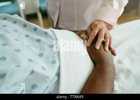 Close-up of doctor comforting senior patient in hospital ward Stock Photo