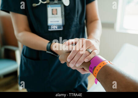 Close-up of nurse holding senior patient's hand in hospital ward Stock Photo