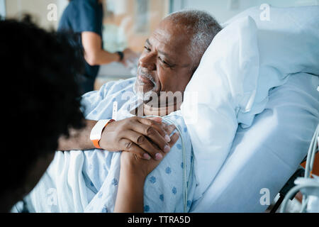 Father consoling daughter while female doctor working in background Stock Photo