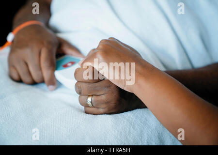 Cropped hand of daughter holding father's hand in hospital ward Stock Photo