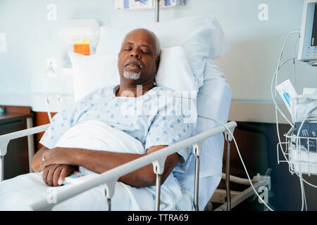 Senior patient sleeping on bed in hospital ward Stock Photo