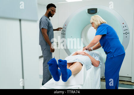 Doctor looking at nurse preparing for MRI Scan on patient in examination room Stock Photo