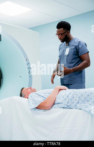 Doctor talking with patient lying on MRI Scanner in examination room Stock Photo