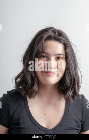 Portrait of smiling teenage girl sitting against white background Stock Photo