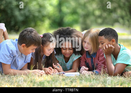 Cute kids reading book on green grass Stock Photo