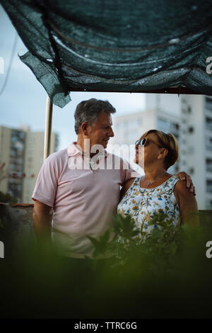 Senior couple looking at each other while standing on building terrace during sunset Stock Photo