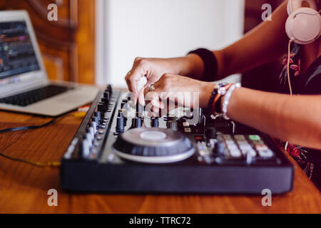 Midsection of female DJ using laptop computer while mixing sound in recording studio Stock Photo