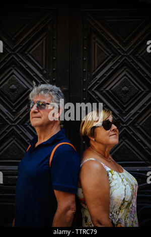 Senior couple wearing sunglasses while standing against closed doors Stock Photo