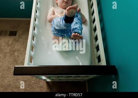 High angle view of boy wearing pant while lying on bunkbed Stock Photo