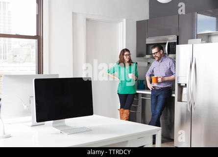 Creative business colleagues holding coffee mugs while discussing in office Stock Photo