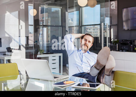 Relaxed businessman sitting with feet up on conference table in board room Stock Photo