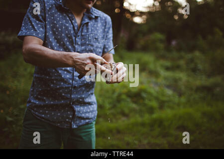 Midsection of man shucking oyster at lawn Stock Photo