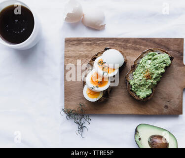 Overhead view of boiled eggs and avocado paste on breads with coffee Stock Photo