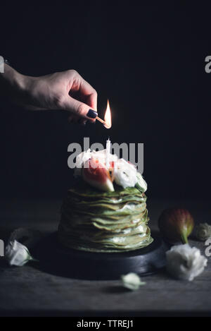 Cropped image of woman lightning candle on pancake Stock Photo