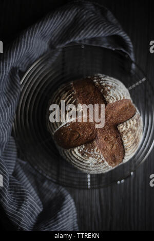 Overhead view of freshly baked bread loaf on metal grate Stock Photo