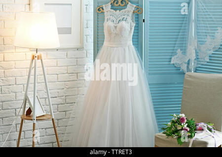 Beautiful wedding dress on hanger in room Stock Photo