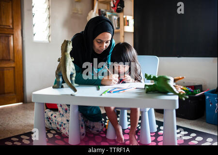 Woman assisting Son in drawing at home Stock Photo