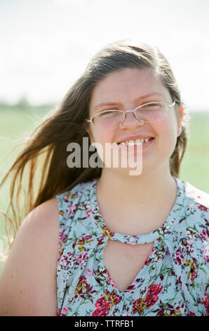 Portrait of overweight teenage girl wearing eyeglasses smiling on field during sunny day Stock Photo