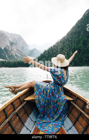 Happy woman enjoying rowboat riding over lake against mountains Stock Photo
