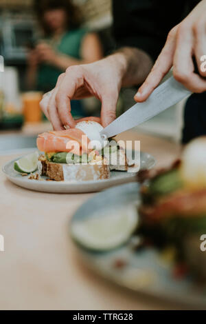 Cropped hands of man cutting boiled egg in plate with kitchen knife Stock Photo