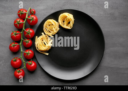 Cherry tomatoes and pasta with black plate on table Stock Photo