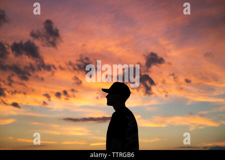 Side view of man standing against cloudy sky Stock Photo