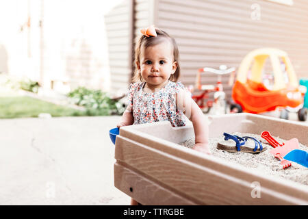 Portrait of baby girl playing with sand in backyard Stock Photo