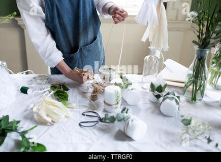 Midsection of woman cutting thread at table in workshop Stock Photo