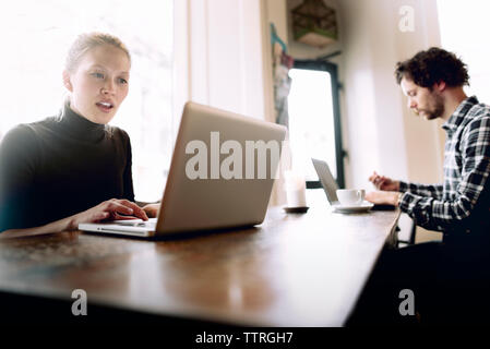 Man and woman using laptop in cafe Stock Photo