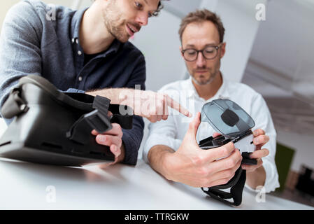 Engineers examining virtual reality simulators in office Stock Photo