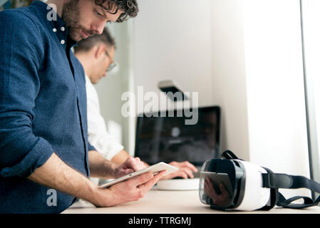 Engineer using tablet computer while colleague using computer in office Stock Photo
