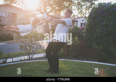 Happy father swinging daughter in backyard Stock Photo