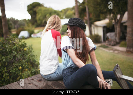 Friends sitting on wooden bench in park Stock Photo