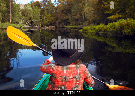 Rear view of woman kayaking in lake at forest Stock Photo