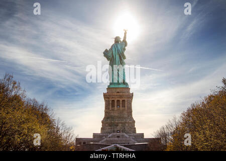 Low angle view of Statue of Liberty against sky on sunny day Stock Photo