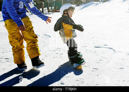 High angle view of father assisting daughter in snowboarding Stock Photo