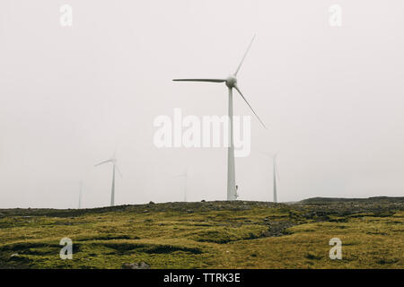 Windmills on field against clear sky Stock Photo