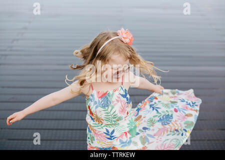 High angle view of happy girl wearing sunglasses spinning on footpath in city Stock Photo