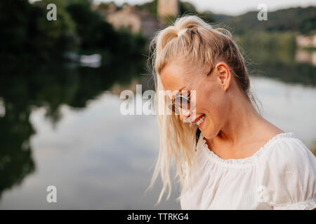 Smiling woman wearing sunglasses standing by Saone River during sunset Stock Photo