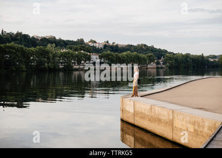 Side view of woman looking at Saone River while standing against cloudy sky during sunset in city Stock Photo