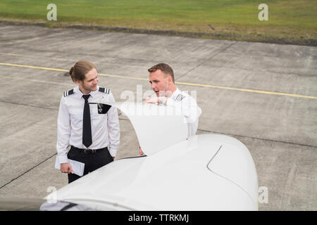 High angle view of engineer showing airplane parts to trainee while standing on airport runway Stock Photo