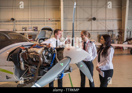 Engineer showing airplane parts to trainees while standing in hangar Stock Photo