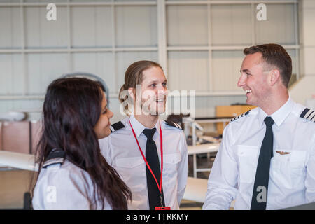 Engineers smiling while standing in airplane hangar Stock Photo