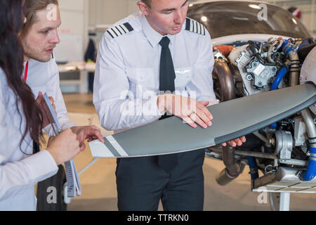 Engineer showing aircraft wing to trainees while standing in hangar Stock Photo