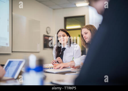 Pilot trainees studying while sitting at desk in classroom Stock Photo