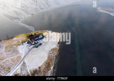 Drone view of country house on coast in snow near water surface in winter Stock Photo