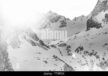 black and white snow covered mountains at sunset with sun flare Stock Photo